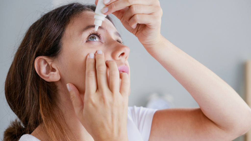 Woman applying lubricating eye drops for dry eye relief before an eye exam or contact lens use at an eye care clinic.