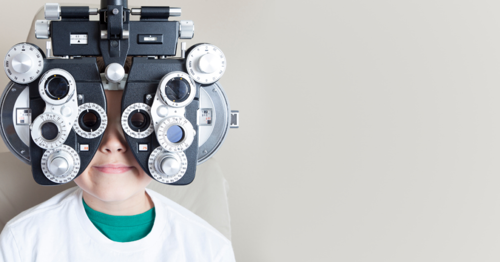 Child looking through a phoropter during a back-to-school eye exam.