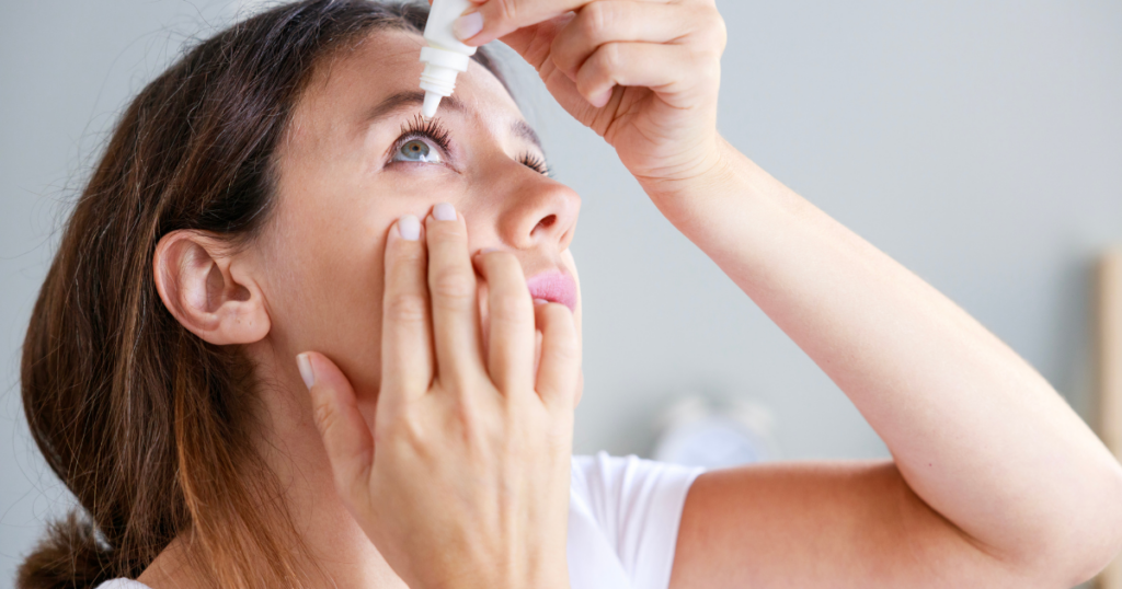 Woman applying eye drops while looking upward.